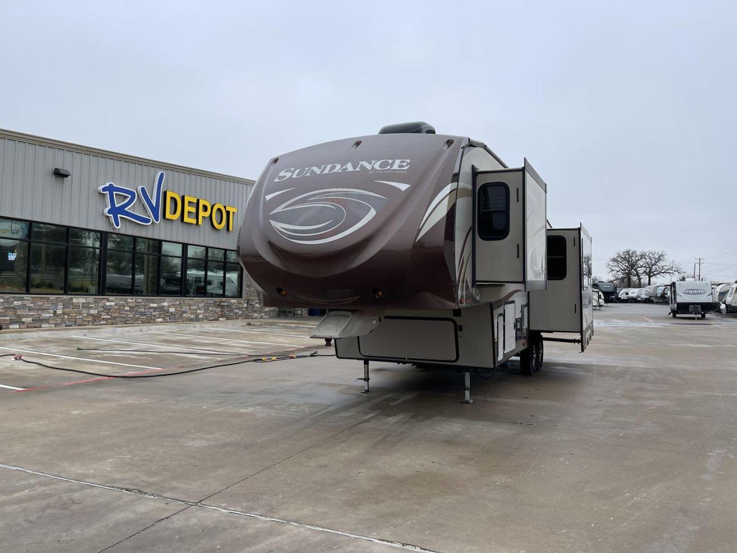 2014 TAN SUNDANCE 2880RLT (5SFSG3320EE) , Length: 32.2 ft. | Dry Weight: 9,750 lbs. | Gross Weight: 13,800 lbs. | Slides: 3 transmission, located at 4319 N Main St, Cleburne, TX, 76033, (817) 678-5133, 32.385960, -97.391212 - This 2014 Sundance Fifth Wheel is just over 32 feet long and 8 feet wide. It has a GVWR of 13,800 lbs and a hitch weight of 2,220 lbs. The exterior of this fifth wheel is a stylish grey with brown, white, and beige decals. This model also has three slides and a 16-foot power-retractable awning. The - Photo#0